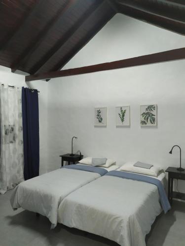 摩亚Moya, Senderos y naturaleza的白色客房的两张床,配有两张桌子