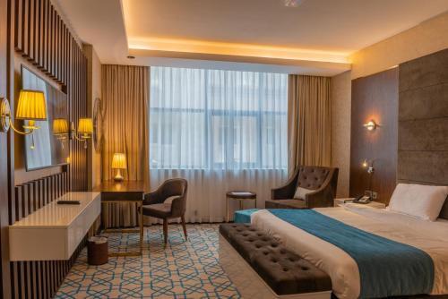马斯喀特Royal Crown Hotel的配有一张床和一张书桌的酒店客房
