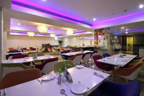 海得拉巴阿苏迦贝斯特韦斯特酒店的餐厅配有白色的桌椅和紫色的灯光
