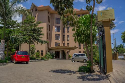 阿鲁沙Panone Hotels - Sakina的停车场内有车辆的建筑物