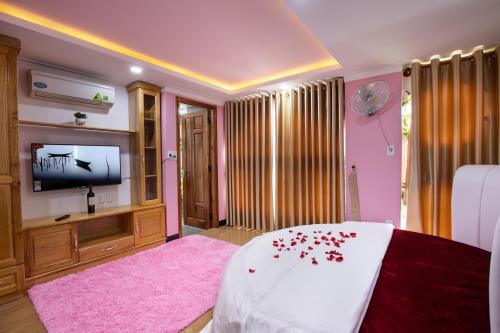 潘郎Kim Hoàn Hotel Phan Rang的一间卧室配有一张粉红色地毯和一台电视。