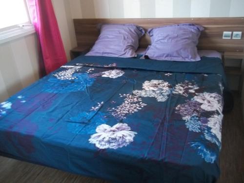 Lesseuxcamping aire du gros pré的一张带蓝色床罩的床,上面有鲜花