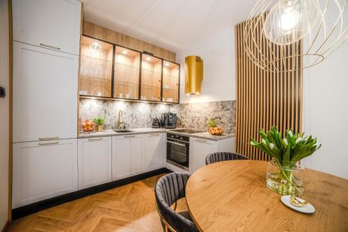 奥尔什丁Apartament Warmiński by RENT4YOU的厨房配有白色橱柜和木桌