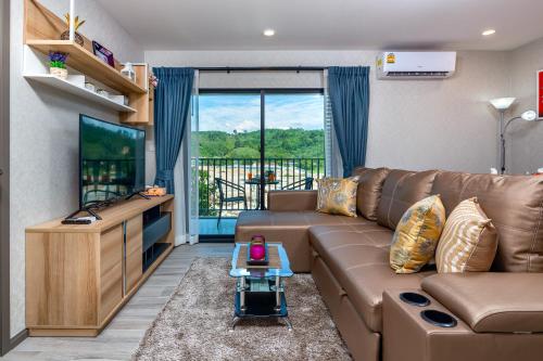 奈扬海滩The Title Residencies Naiyang Beach的客厅配有棕色沙发和电视