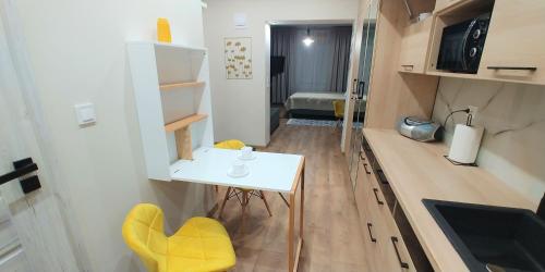 海乌姆诺Apartament CCH - Biskupia的小厨房配有白色的桌子和黄色的椅子