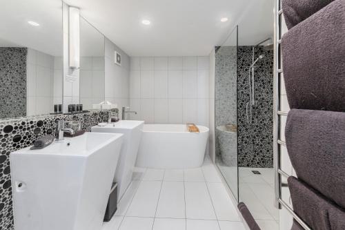 罗托鲁瓦黑天鹅湖畔精品酒店的白色的浴室设有2个盥洗盆和1个浴缸。