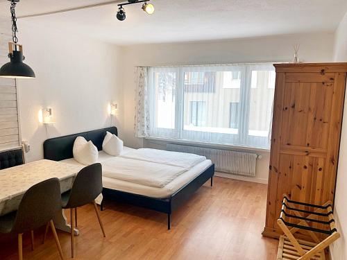 圣莫里茨Zentrale gemütliche Wohnung St Moritz - A212的一间卧室配有一张床、一张桌子和一个窗户。