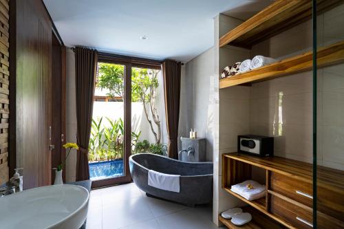 库塔The Calna Villa Bali的带浴缸的浴室和大窗户