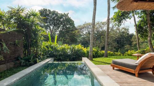乌布优布达玛雅假日温泉酒店的花园内的游泳池,带椅子和庭院