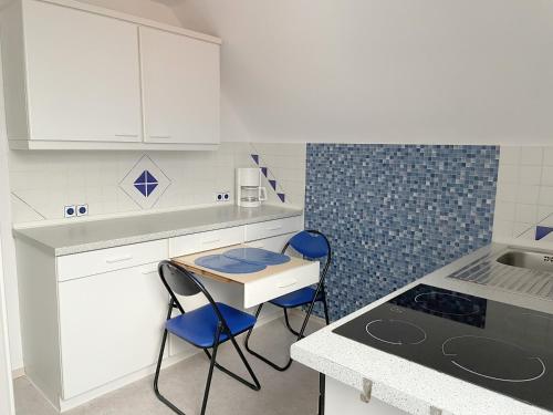 巴特塞森多夫Fewo Haus Piepenbreier的厨房配有白色橱柜和蓝色椅子