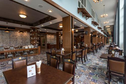 攀牙Le Erawan Phang Nga Hotel的一间带木桌椅的餐厅和一间酒吧