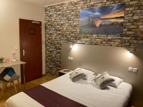 古尔奈昂布赖诺曼底酒店的一间卧室设有一张床和砖墙
