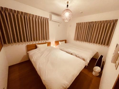 富士河口湖L's Mt.Fuji vacation rental的一间卧室配有两张床和吊灯。