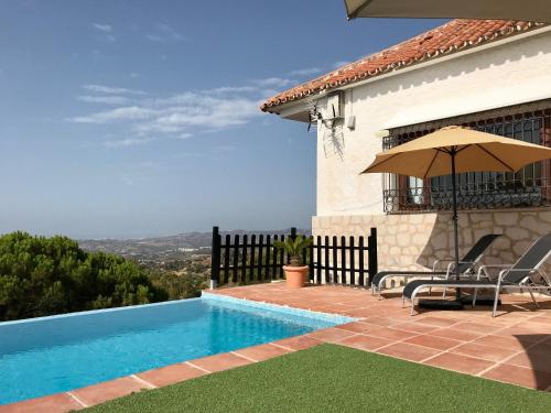米哈斯Villa FenaVista的一座带游泳池和遮阳伞的房子