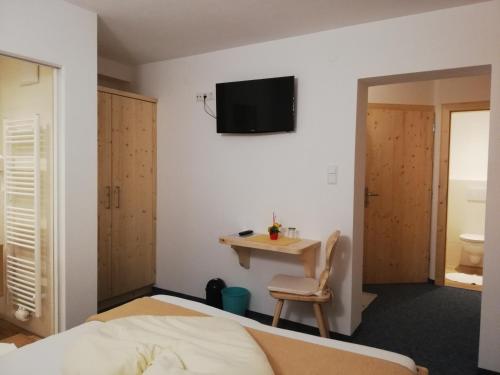 斯拉德明Gästehaus Pürstl-Kocher的一间卧室配有一张床和一张桌子,墙上配有电视。