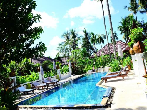查龙Cocoville Phuket - SHA Plus的一个带椅子和棕榈树的度假村游泳池
