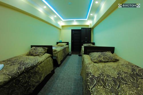 ChkalovskHostel Buston的一间设有三张床和蓝色灯光的房间