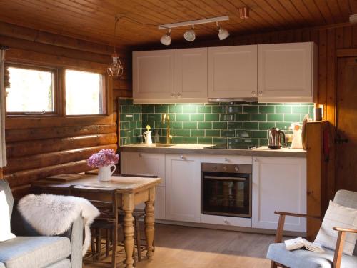 斯特拉西尔Hillside Log cabin, Ardoch Lodge, Strathyre的厨房配有白色橱柜和带壁炉的桌子。