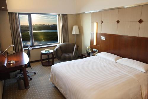 哈尔滨哈尔滨香格里拉的配有一张床、一张书桌和一扇窗户的酒店客房