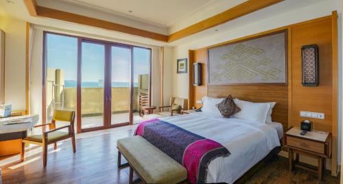 三亚海旅·君澜三亚湾迎宾馆的一间卧室配有一张床、一张书桌和一个窗户。