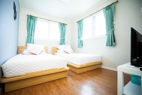 仁川市雨靴宾馆的配有两张床铺、蓝色窗帘和电视的客房