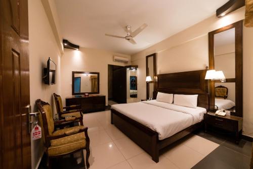 伊斯兰堡Laraib Inn Hotel的一间卧室配有一张床、一把椅子和镜子