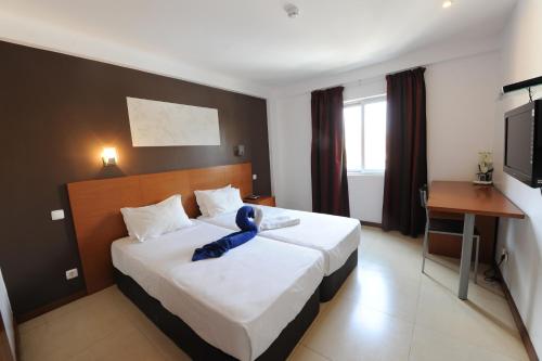 罗安达罗安达酒店的一间卧室,配有一张带蓝色泰迪熊的床