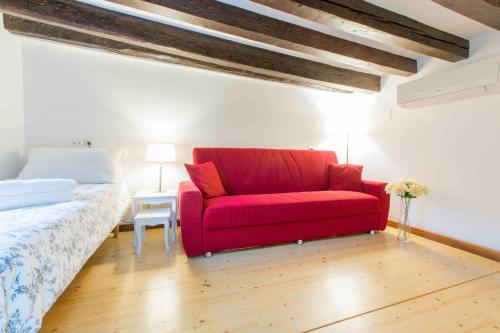 威尼斯CA CICOGNA air conditioning and fast WiFi, central location apartment的一张红色的沙发,位于带床的房间