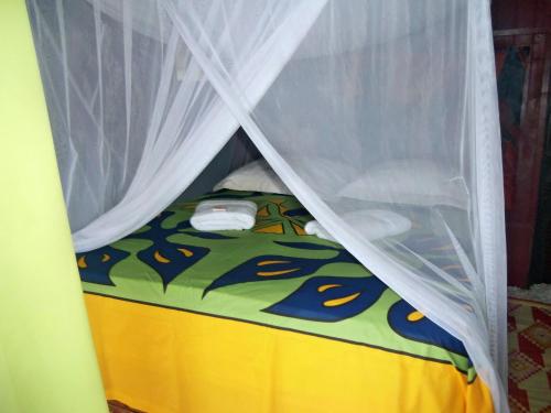 Parea纳黑托叶山林小屋的一张带天蓬和黄色床垫的小床