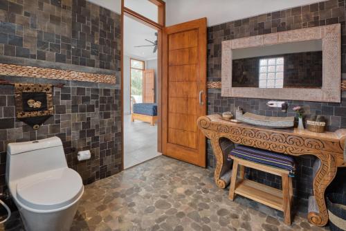 乌布Wake in Paradise Lebah Villas Pool Kitchen Spa的一间带卫生间、水槽和镜子的浴室