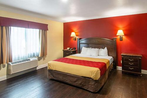 长滩Econo Lodge Long Beach I-405的酒店客房,设有一张红色墙壁的大床