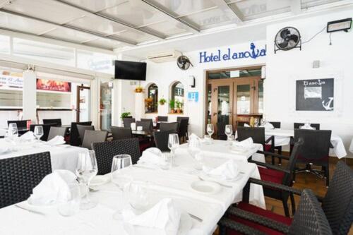 卡拉宏达Hotel El Ancla的一间设有白色桌椅的用餐室