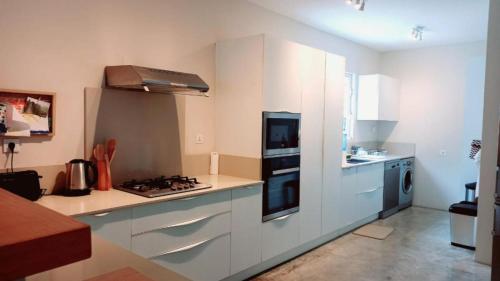 罗驰诺尔Villa Ximun的厨房配有白色橱柜和炉灶烤箱。