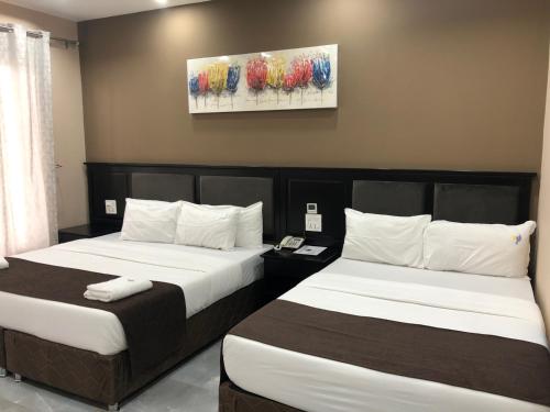 卢萨卡Palm Kalash Hotel的两张位于酒店客房的床,配有两张sidx sidx单人床