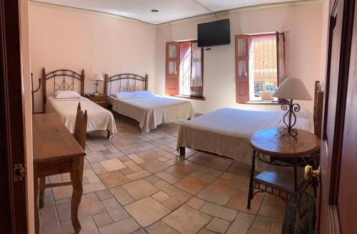 瓦哈卡市Posada Regional的一间卧室配有两张床和一台平面电视