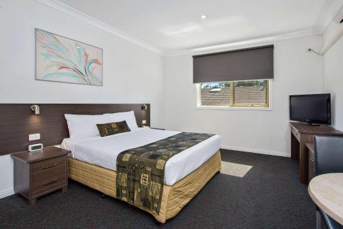 丹德农Comfort Hotel Dandenong的一间卧室配有一张床和一台平面电视