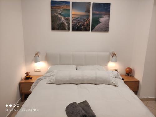 阿拉德ARAD-DEAD SEA BASHIRIS PLACE的卧室配有一张白色床,墙上挂有三张照片