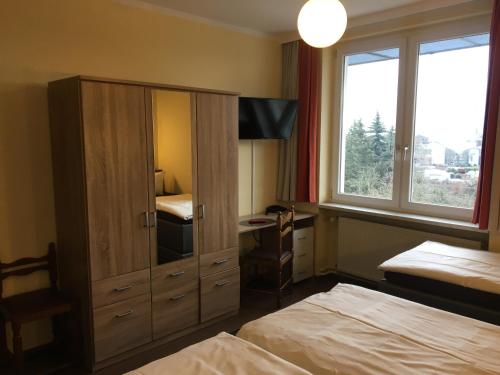 奥斯纳布吕克西门子酒店的一间卧室配有两张床,一个橱柜配有书桌