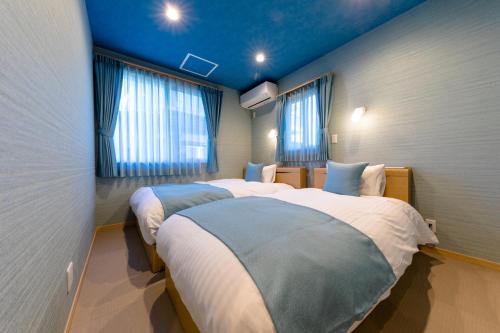 富士河口湖02 Resort Club -蒼SOU-的配有2张床的蓝色天花板和窗户。