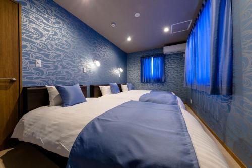 富士河口湖01 Resort Club -結YUI-的配有两张床铺的蓝色墙壁和蓝色窗帘