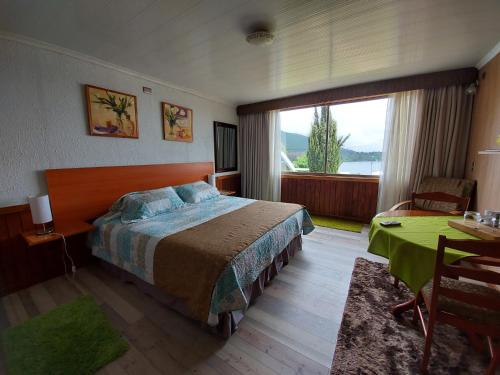 卡涅特Complejo Pehuen Lago Lanalhue的一间卧室配有一张床、一张桌子和一个窗户。