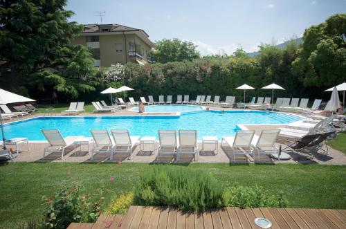 加尔达湖滨路易斯酒店的庭院内一个带椅子和遮阳伞的游泳池