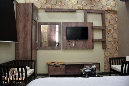 卡拉奇Diplomat Inn Hotel的一间设有床铺和墙上电视的客房