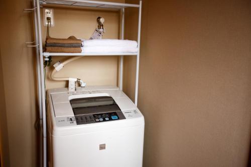 Fukumitsuguesthouse絲 -ito-ゲストハウスイト的小房间里的洗衣机和烘干机