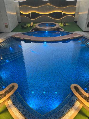 麦纳麦Bahrain bay studio的大楼内带蓝色灯光的大型游泳池