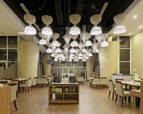 北加浪岸Howard Johnson By Wyndham Pekalongan的用餐室配有桌椅和吊灯。