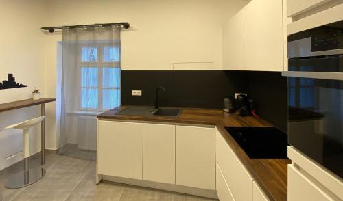 克塞洛Hősök Tornya Apartman的厨房配有白色橱柜和水槽