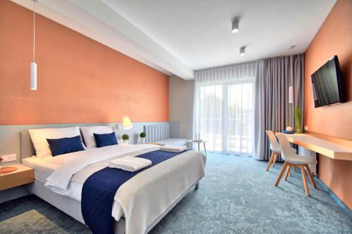 梅尔诺Savana Resort Mielno的酒店客房设有一张大床和一张书桌。