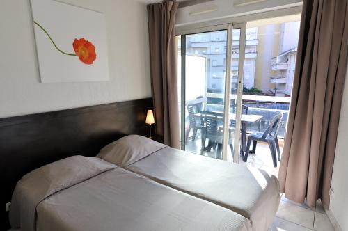 戛纳渣油戛纳法斯迪瓦勒酒店的一间卧室配有一张床,阳台配有桌子