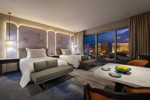澳门澳门新濠天地-颐居的酒店客房设有一张大床和一张桌子,还有一间享有美景的客房。